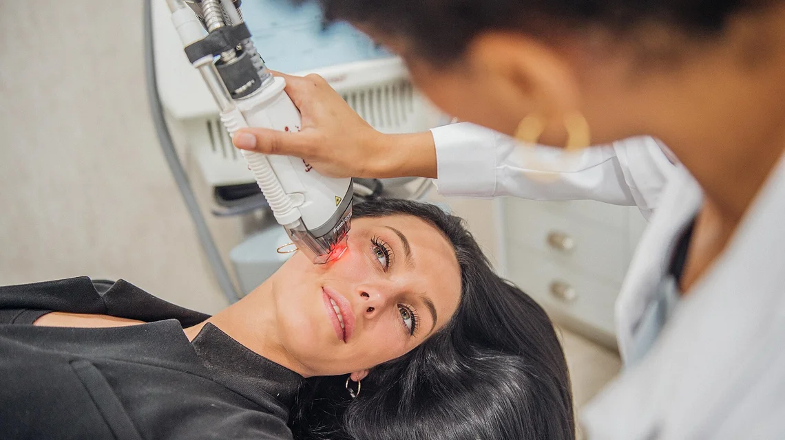 Clinician performing a facial aesthetic laser treatment on a patient
