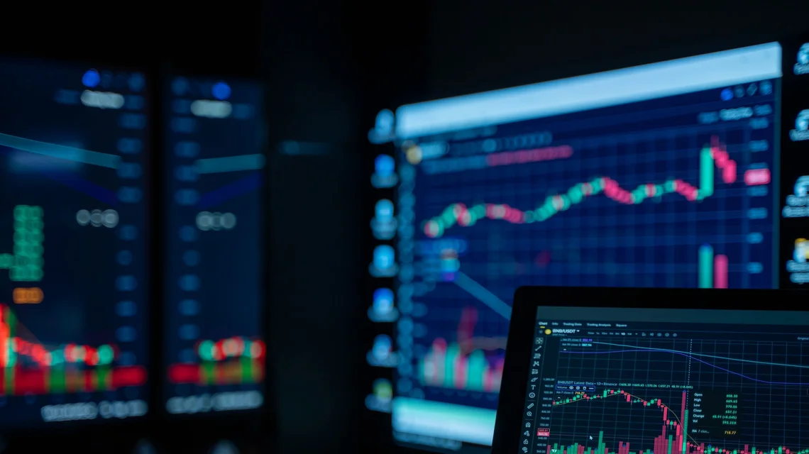 Portfolio manager reviewing fund performance data on trading screens in a DIFC office