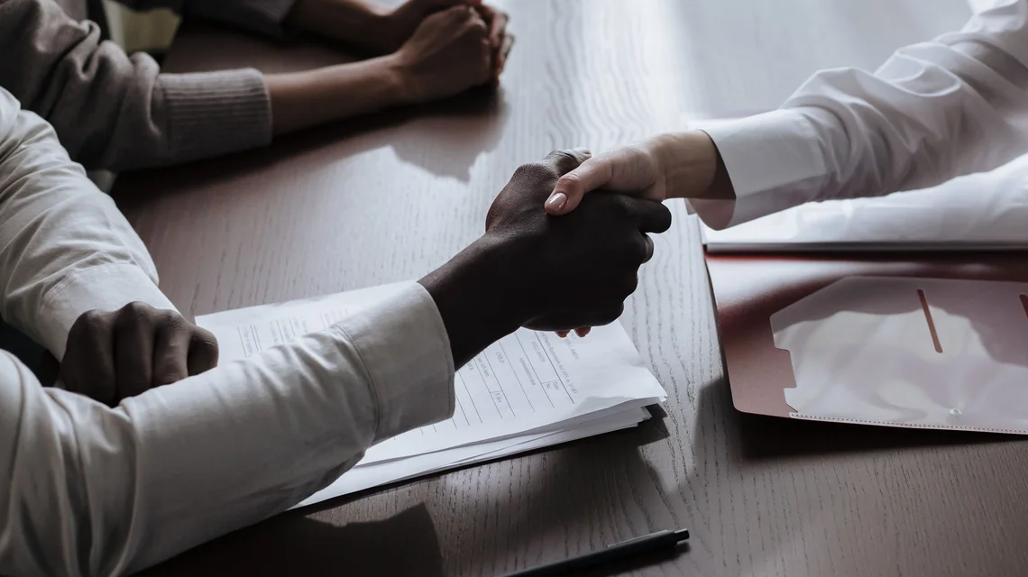 Business handshake over a signed agreement in an office