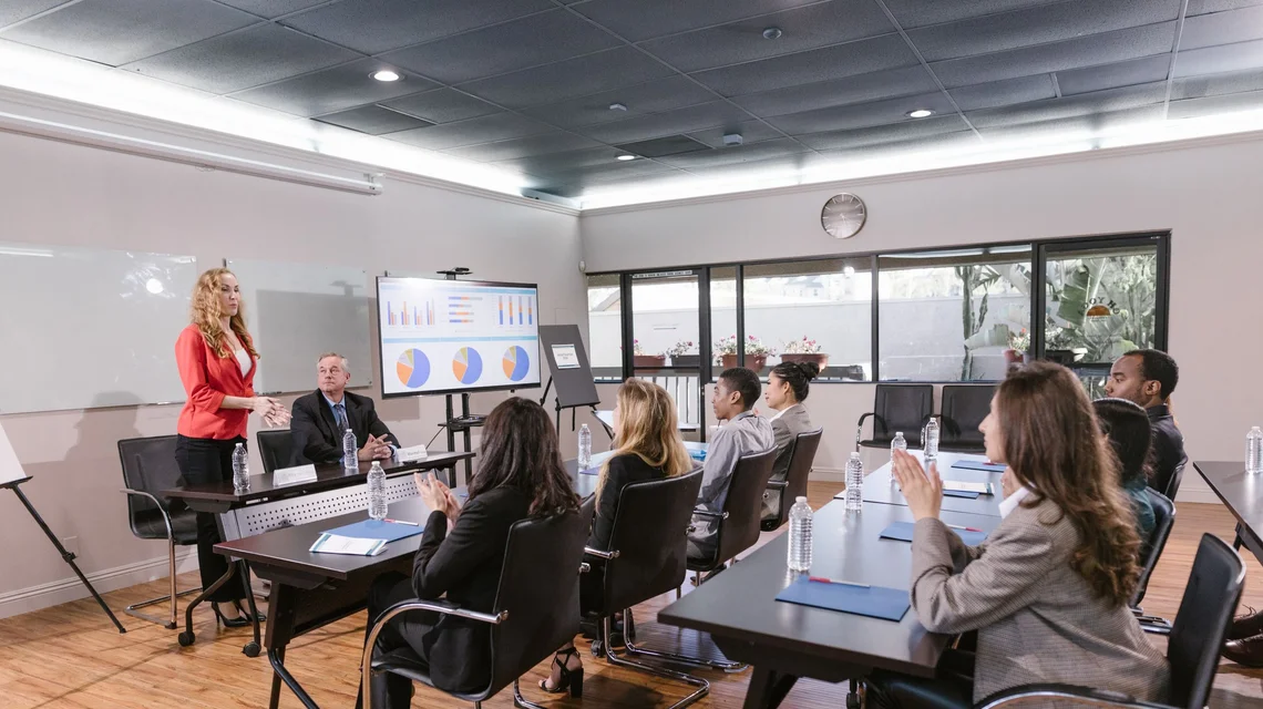 Business consultant leading a paid corporate workshop for a client company's staff in a Dubai meeting room