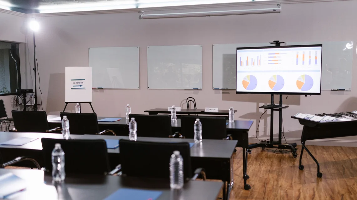 Empty Dubai training room set up with desks and a presentation screen ahead of an authorised course