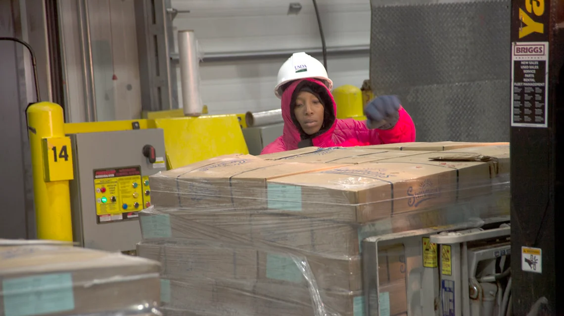 A worker handling palletised cargo at a warehouse