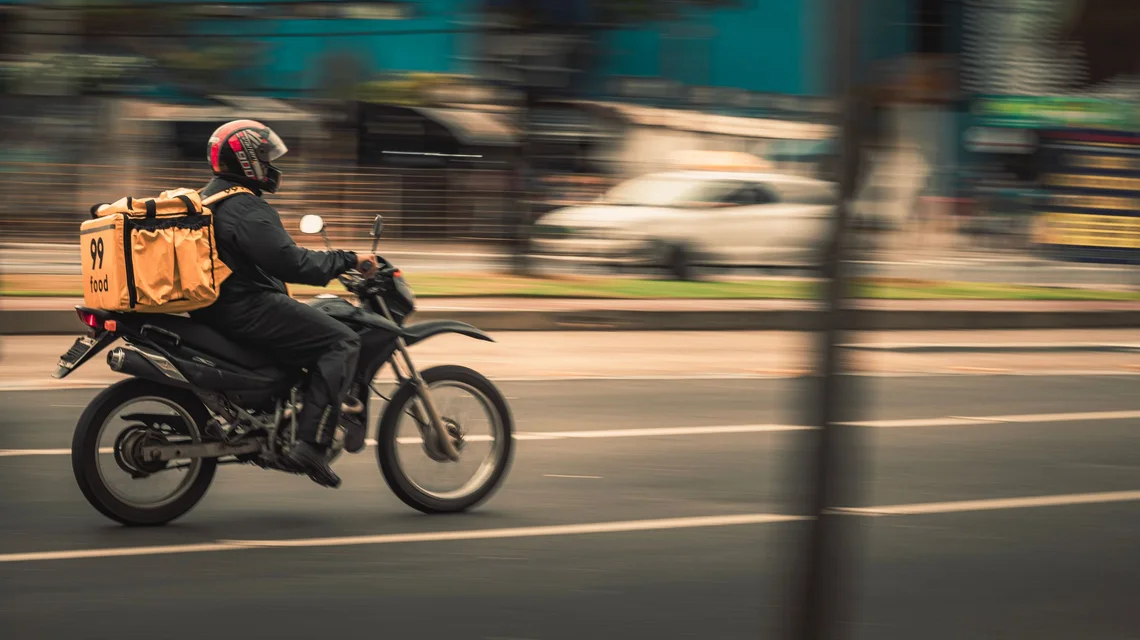 Delivery rider riding a commercial motorbike with an insulated delivery box through Dubai traffic