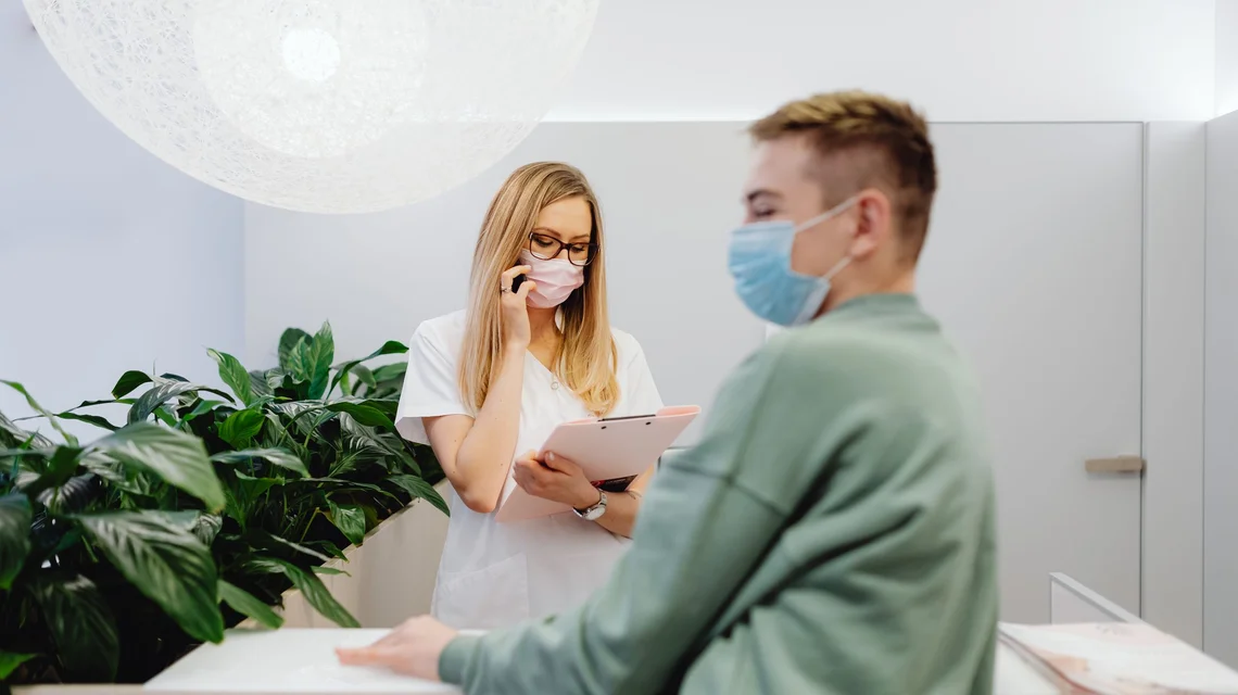 A doctor reviewing a patient file at a clinic reception desk in Dubai