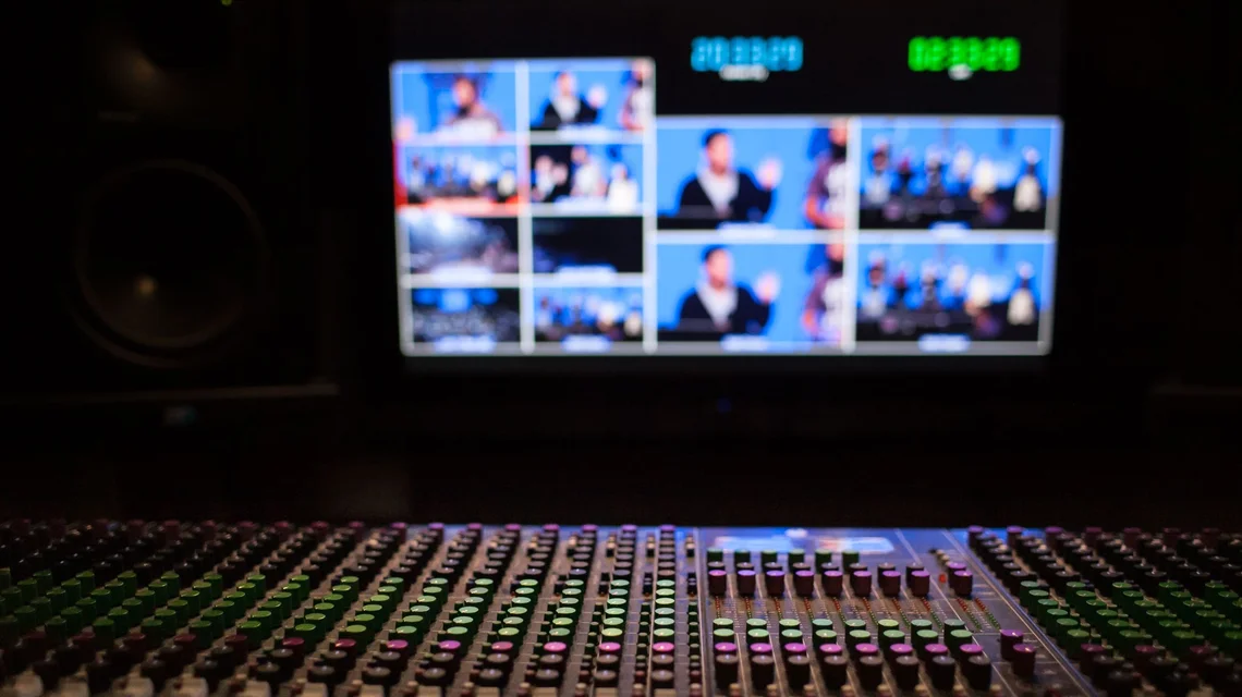 A broadcast control room with a monitor wall and vision-mixing desk