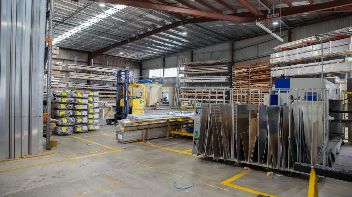Technicians in an electronics production area assembling circuit boards at workbenches under bright task lighting