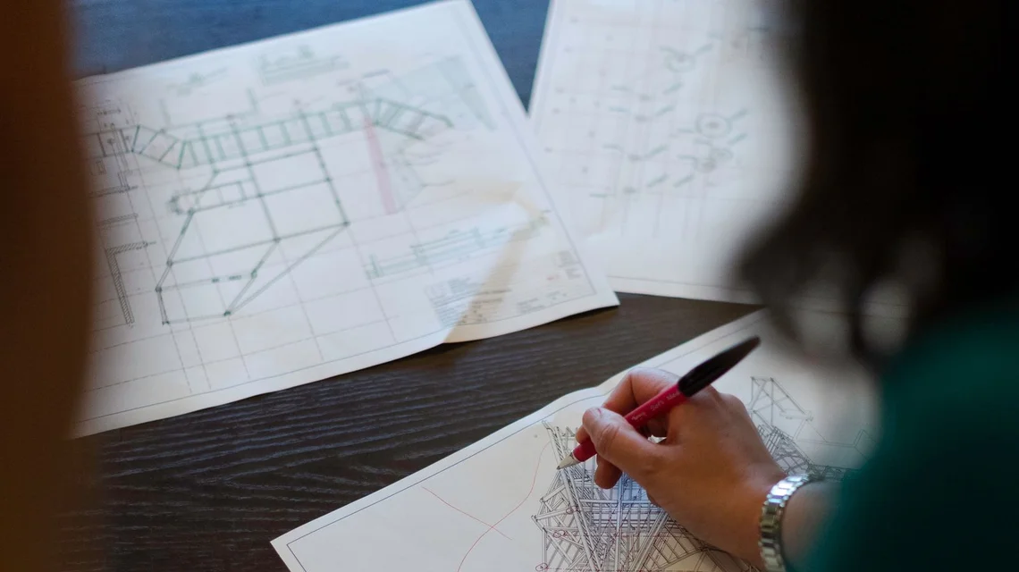 An engineer marking up structural drawings in a design office