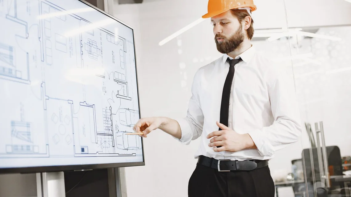An engineer in a hard hat presenting building plans