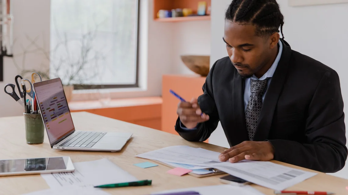 A business owner reviewing printed penalty notices and financial statements at a desk