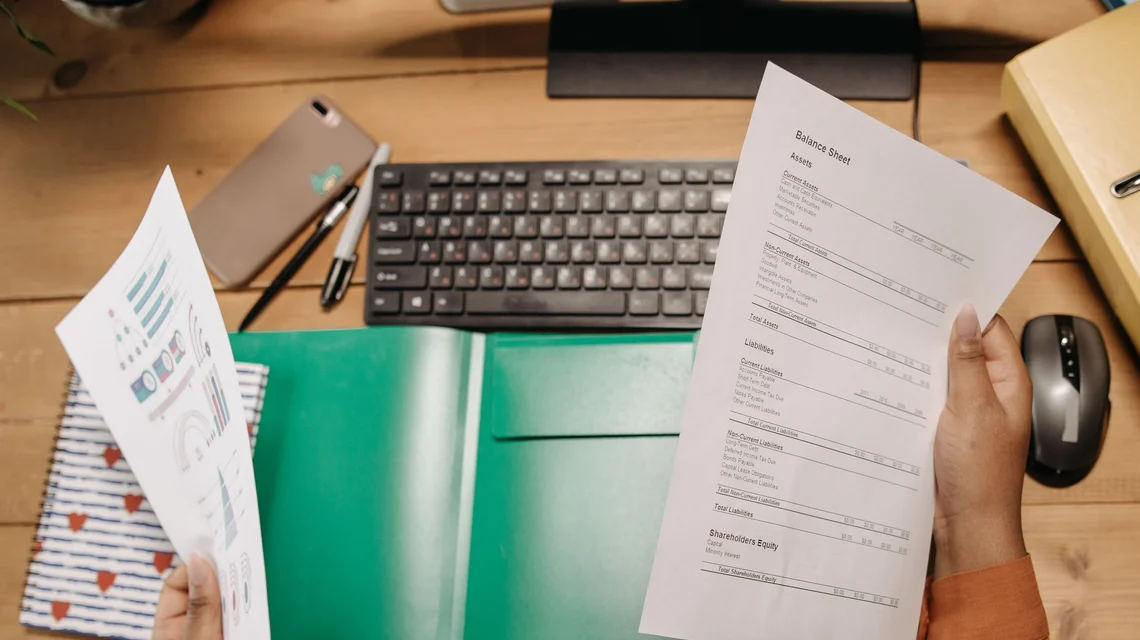 Person reviewing printed company registration documents and a laptop at an office desk
