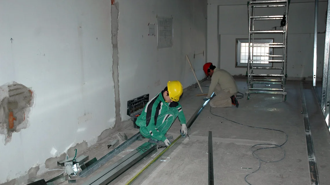 Workers fitting out a commercial interior with partitions and ceiling