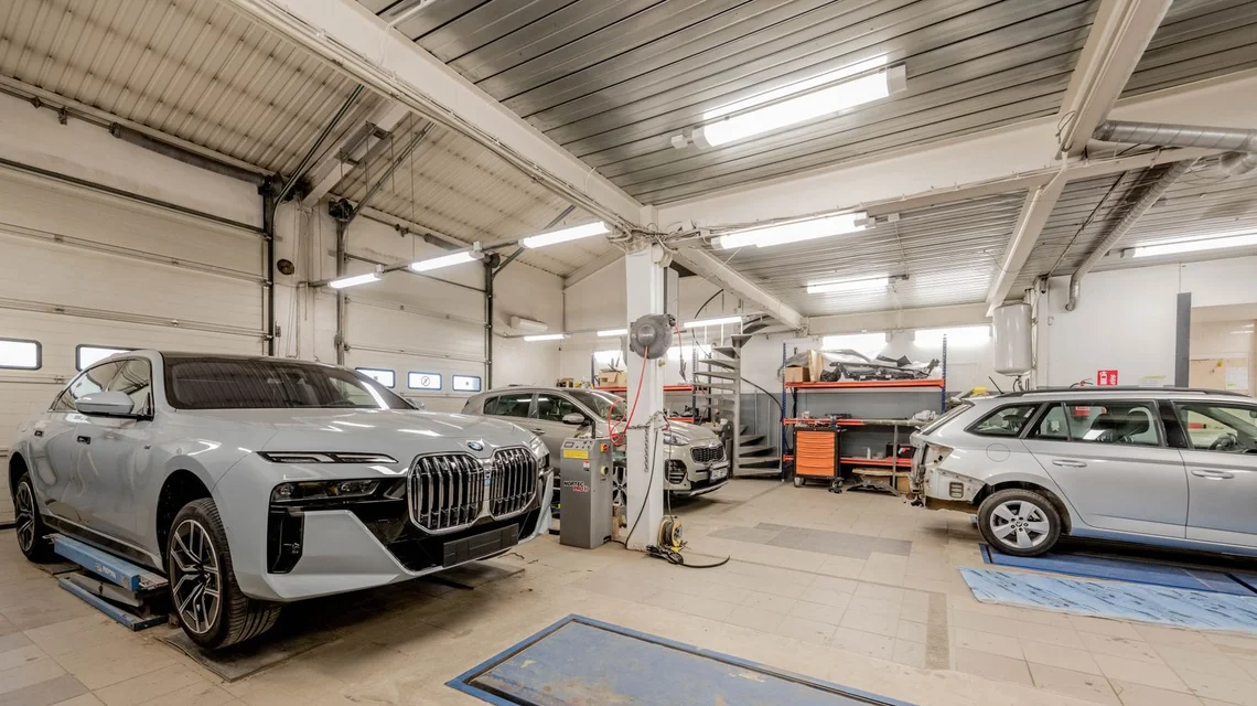 Row of cars being serviced in a busy modern auto workshop
