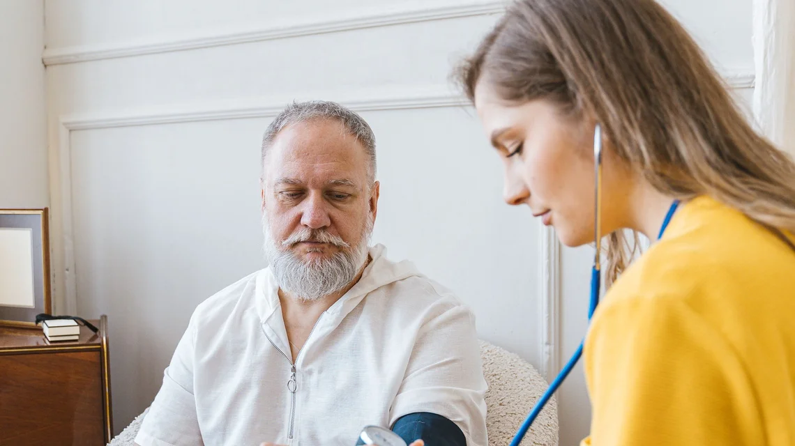 A licensed nurse taking an elderly patient's blood pressure during a home visit