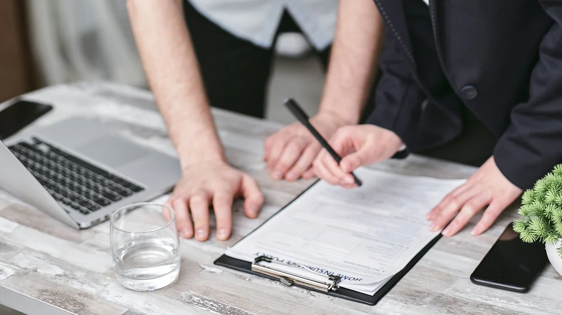 Insurance broker reviewing a policy document with a client at a meeting table