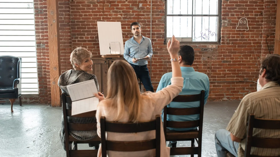 Instructor leading a small group workshop around a table in a Dubai training room