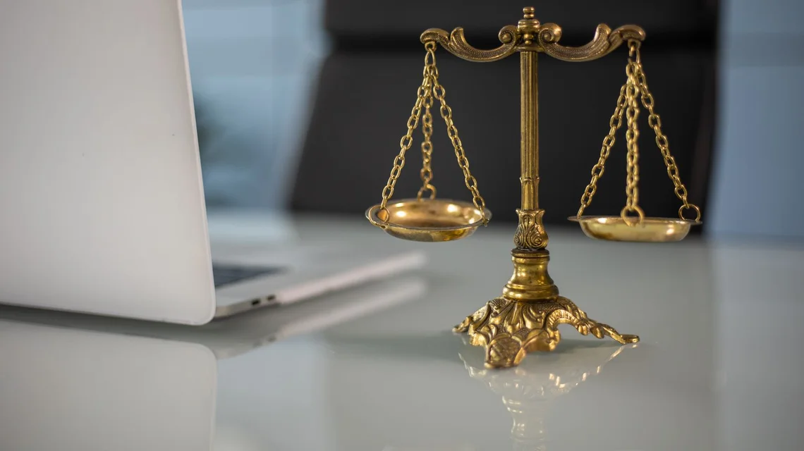A brass scales-of-justice statue on a legal consultant's desk