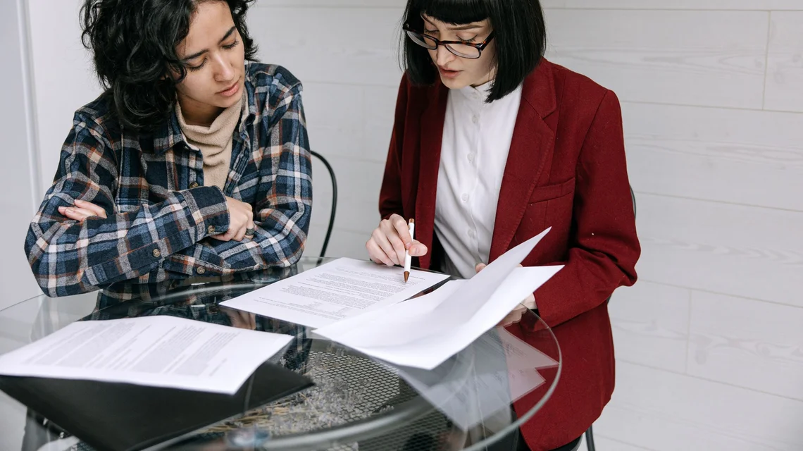 Two colleagues reviewing company incorporation documents across a meeting table