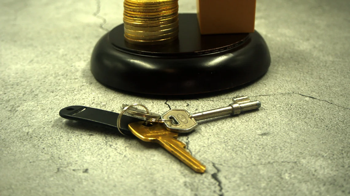 A model house on stacked coins with keys