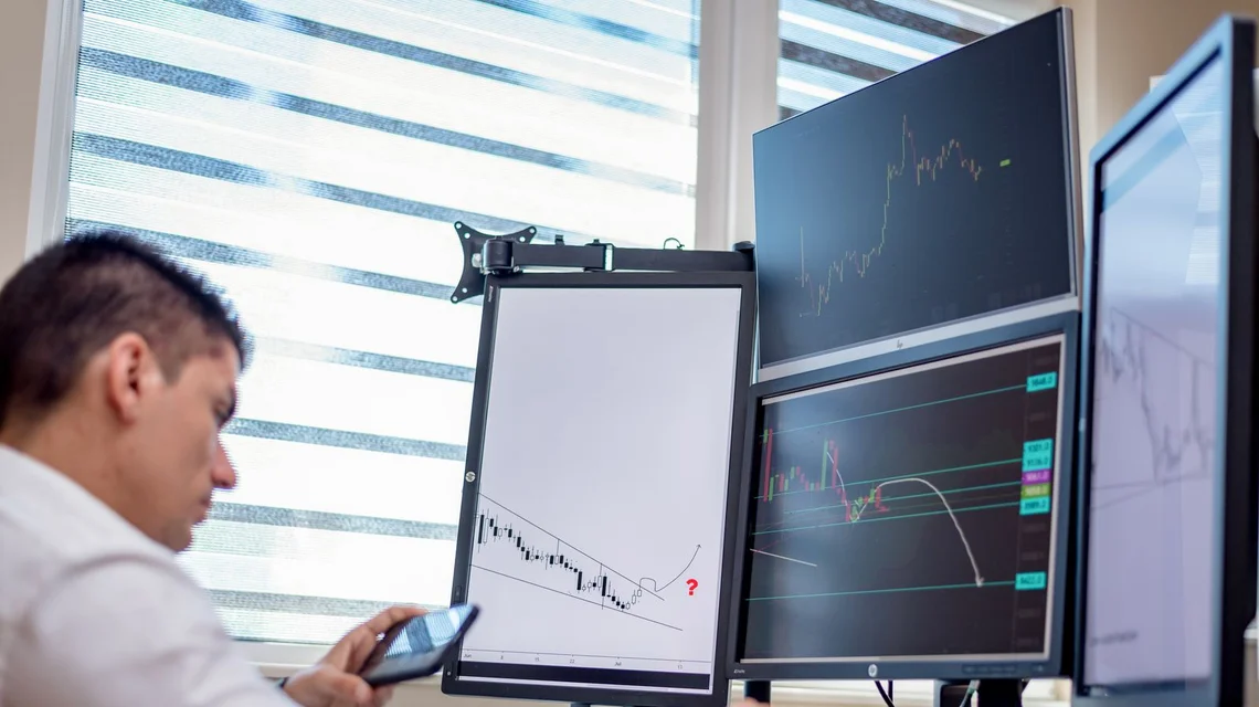 Trader monitoring energy market prices on multiple screens