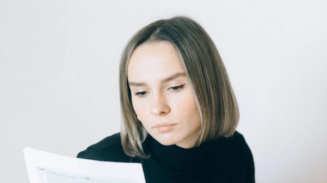 A person reviewing a printed privacy policy and consent form alongside a laptop at a desk
