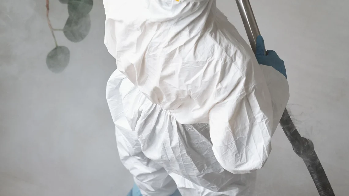 A pest control technician fogging a home interior in protective gear