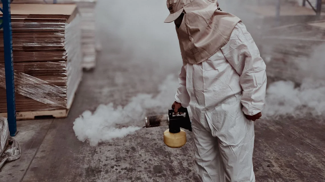 A pest control technician fumigating a warehouse in protective gear