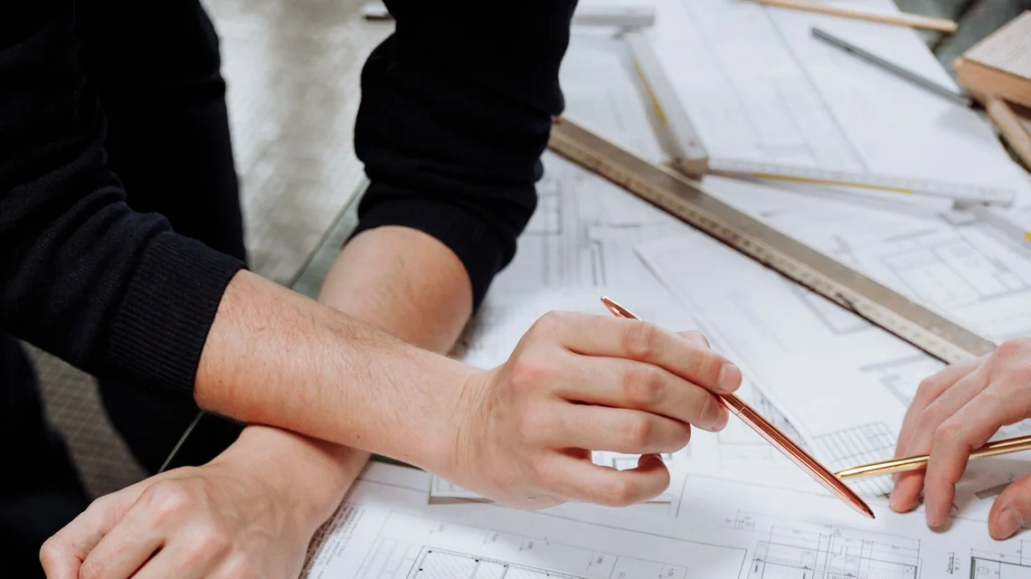 A developer and architect reviewing building plans over technical drawings