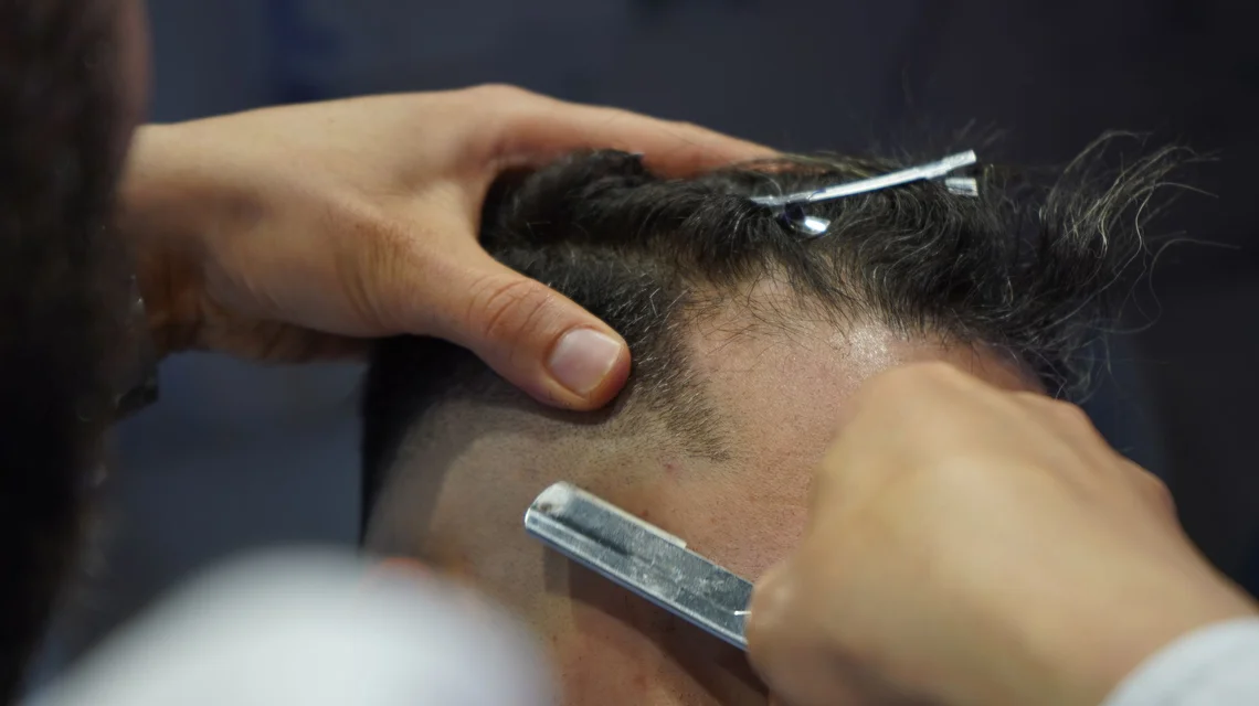 Barber working a razor along the neckline of a male client in a licensed Dubai gents salon