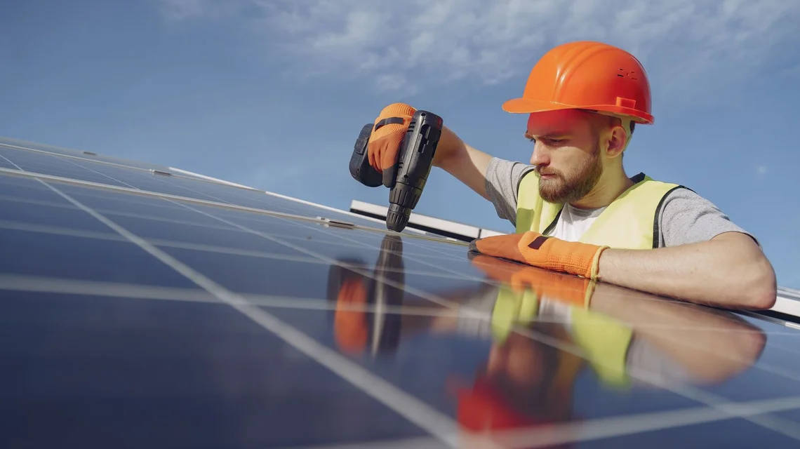 Technicians installing solar panels on a rooftop in the Gulf sun