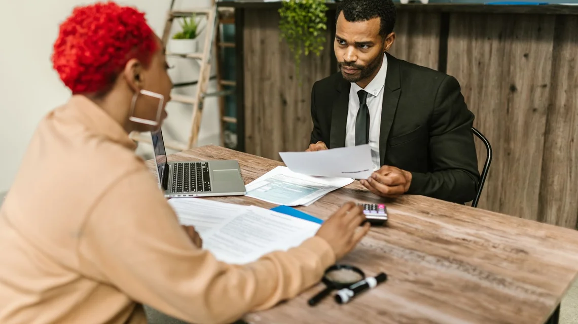 A tax consultant reviewing documents with a client at a desk