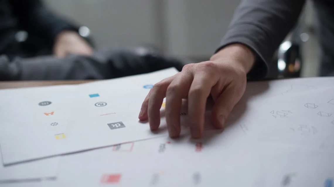 A designer reviewing logo concepts on paper for a brand identity