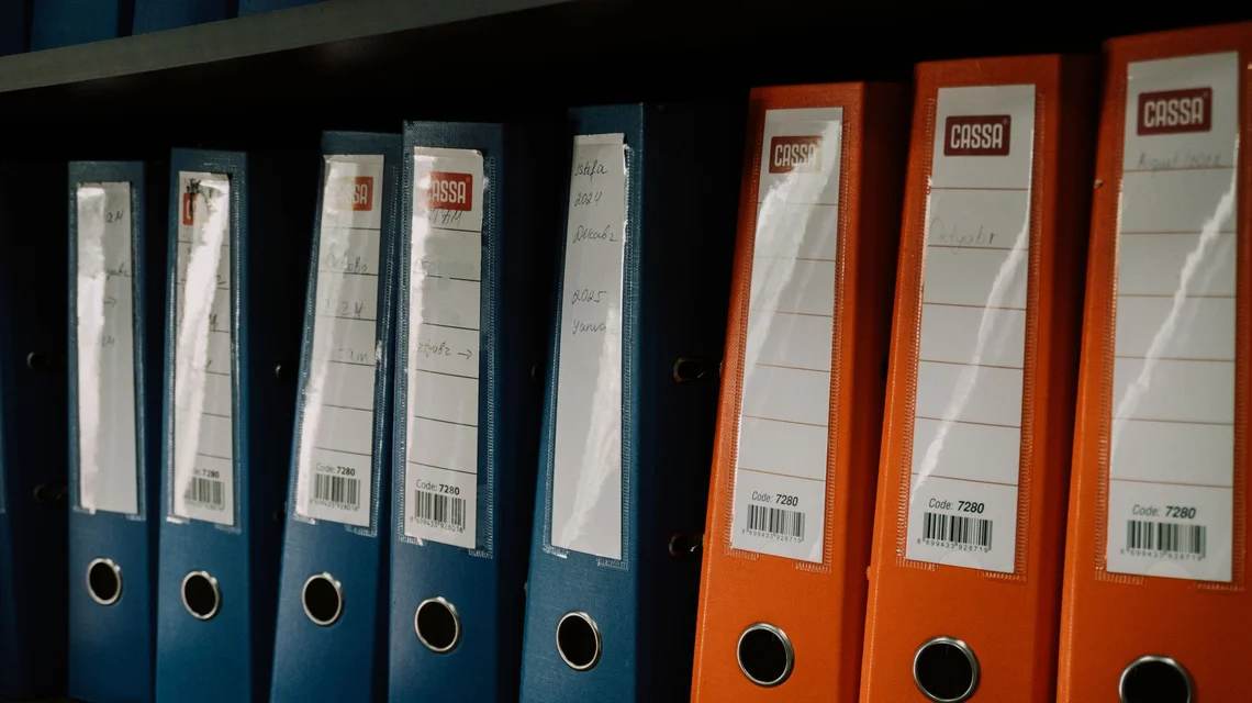 A person comparing two separate sets of financial statements on a laptop and printed pages