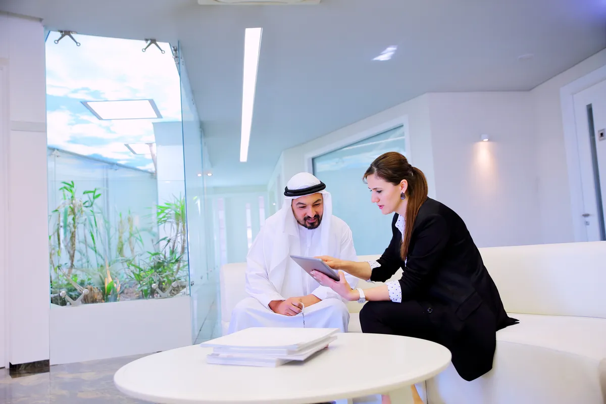 An advisor and client reviewing financial statements and bound reports together in Dubai