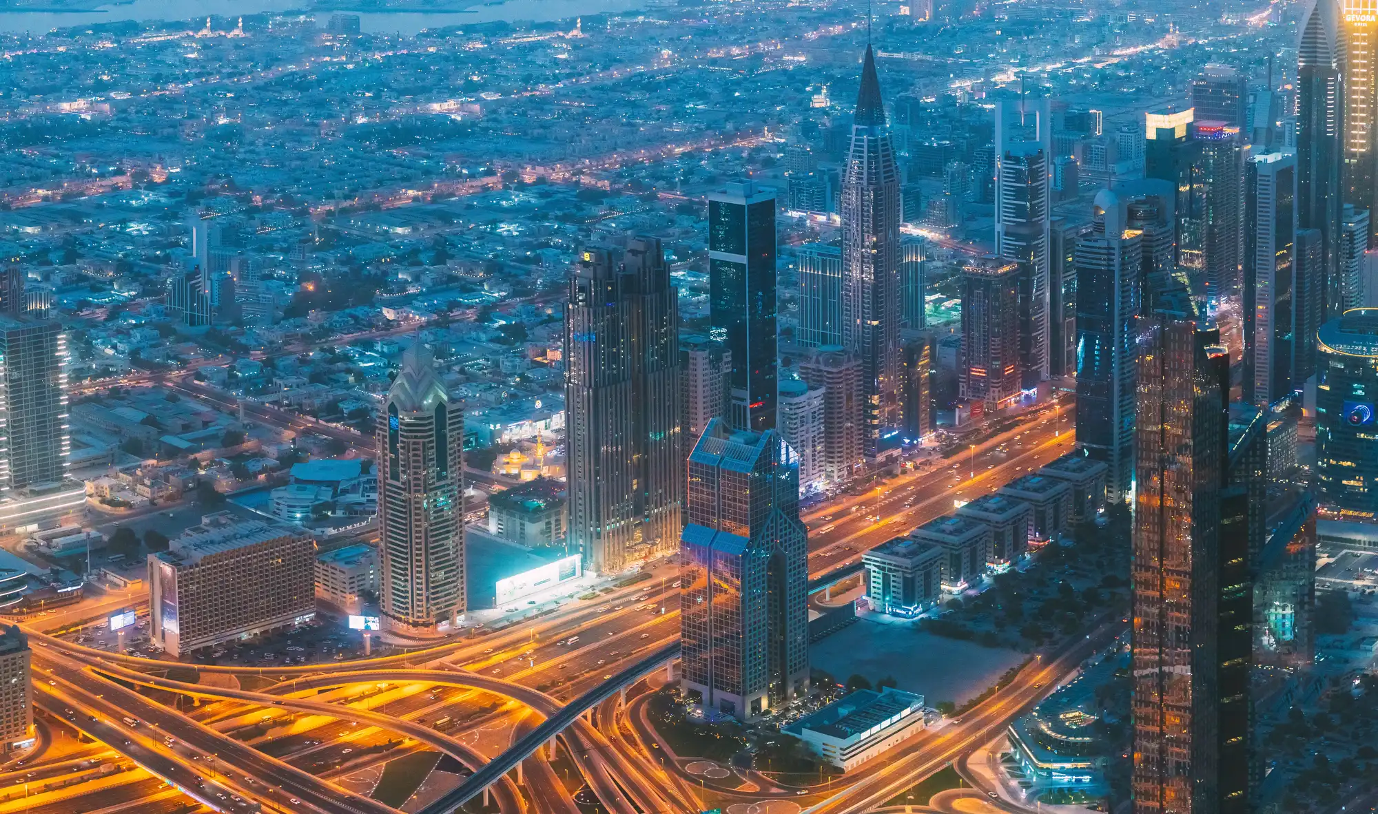 Aerial view of the Dubai cityscape at dusk with light trails along Sheikh Zayed Road