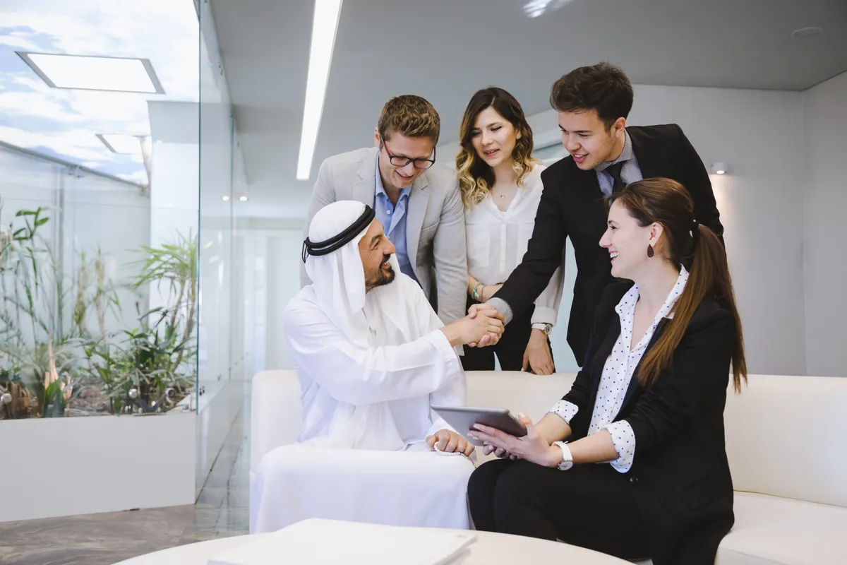 A business consultant welcoming a client with a handshake in Dubai