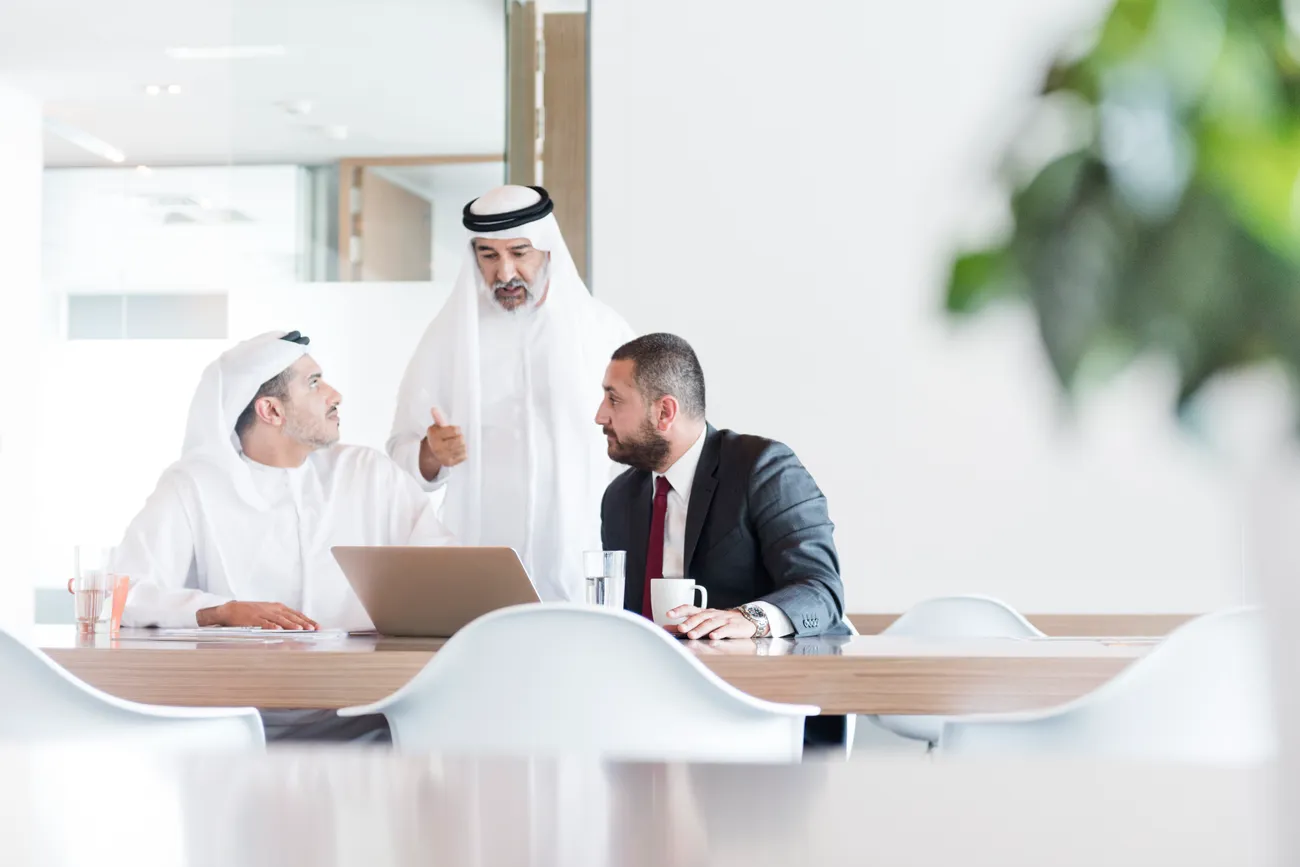 Advisors and a client working through company filings together in a bright Dubai office